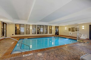 Una piscina interior con agua cristalina, suelo de baldosas y una silla para salvavidas.