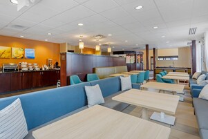 Un restaurante moderno con asientos azules, mesas de madera y una zona de cocina.
