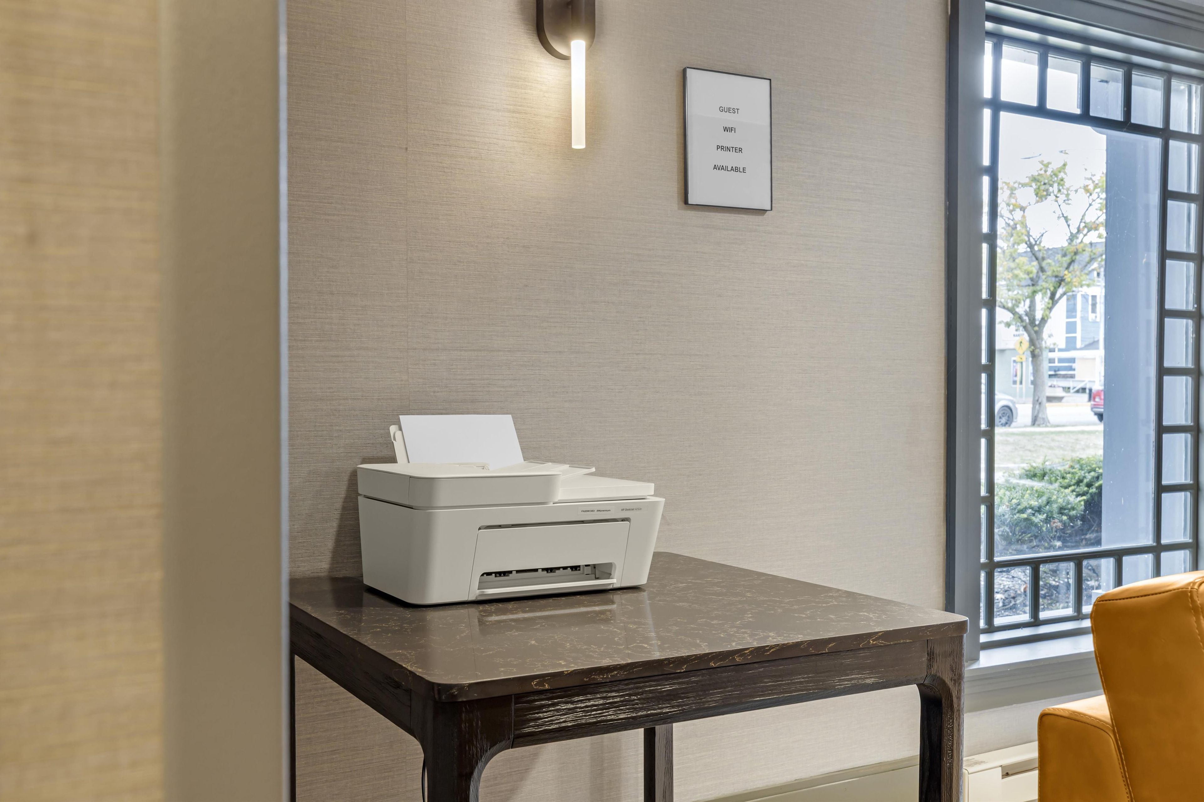 A printer on a table with a sign indicating guest WiFi and printer availability.