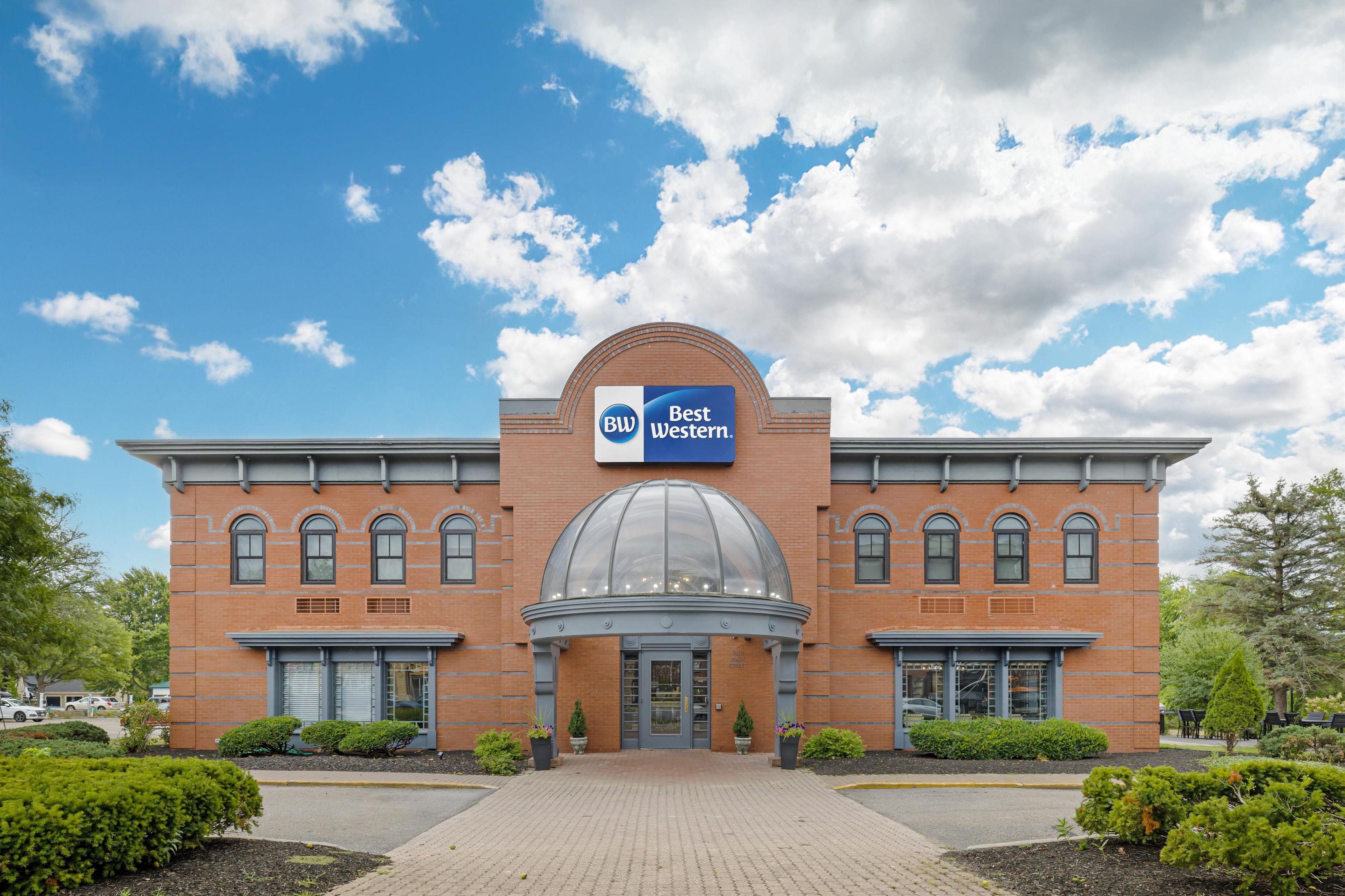 Een Best Western hotel met een gevel van baksteen, een centrale koepel en een helderblauwe lucht.