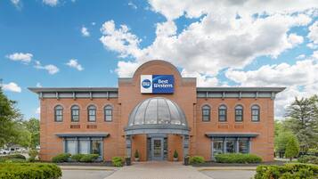 Een Best Western hotel met een gevel van baksteen, een centrale koepel en een helderblauwe lucht.