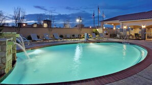 Piscina com espreguiçadeiras e área de estar coberta.