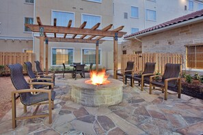 An outdoor patio with stone flooring, a fire pit, and wicker chairs. - Residence Inn Odessa (Odessa)