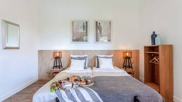 A neatly arranged bedroom with a bed, bedside tables, a wardrobe, and two framed pictures on the wall.