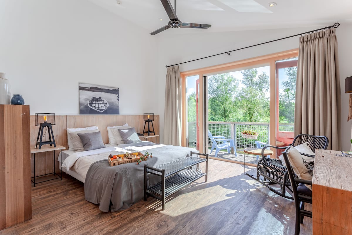 Un dormitorio moderno con una cama grande, un escritorio y un balcón con mobiliario exterior.