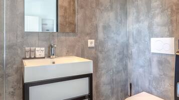 Un baño moderno con un espejo grande, un lavamanos blanco y un inodoro.