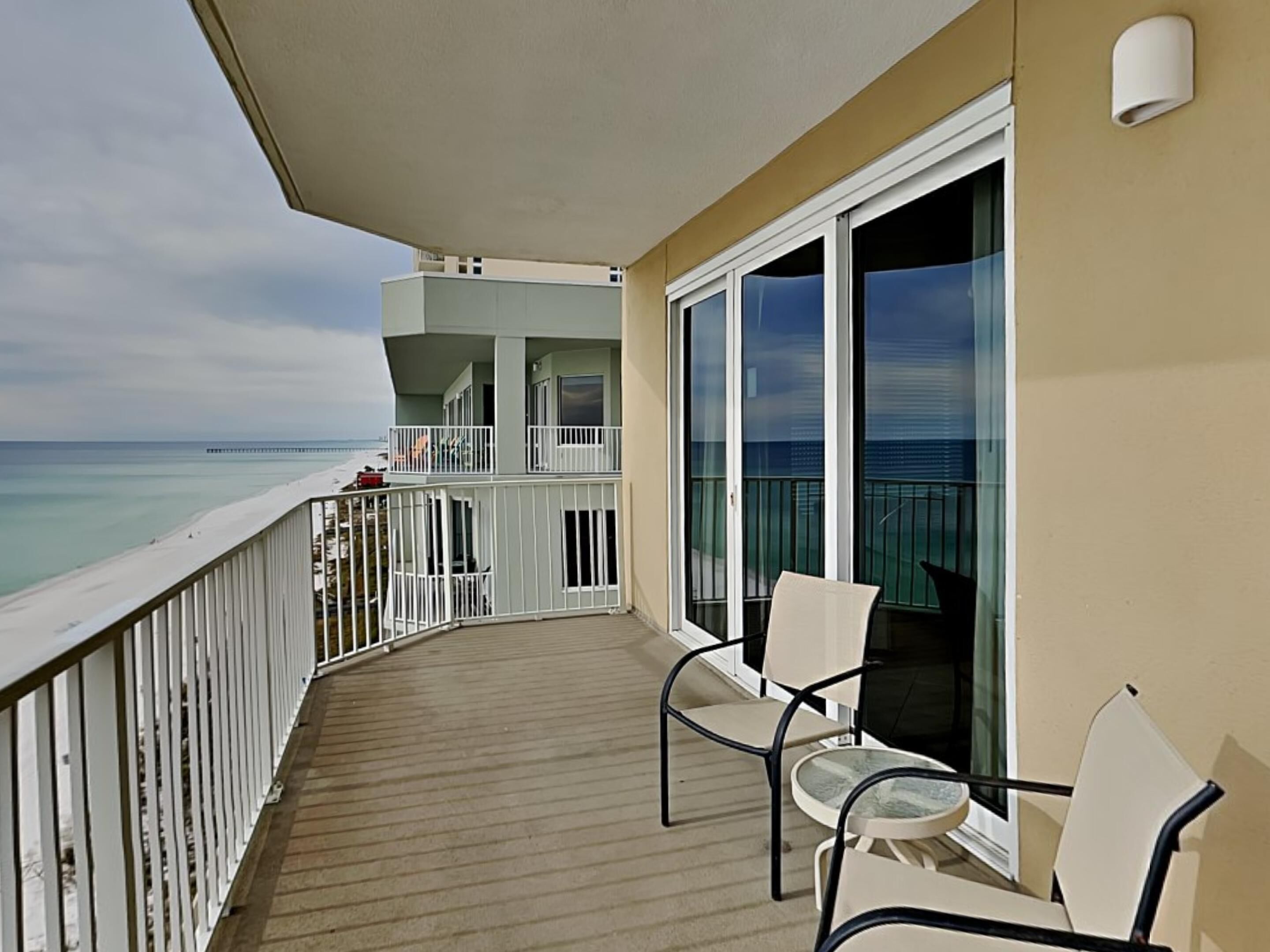 A balcony with a view of the ocean, featuring two chairs and a table.
