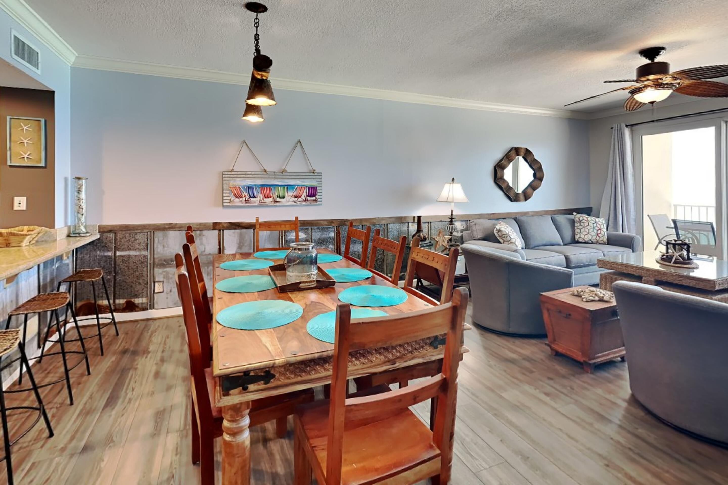 A dining area with a wooden table and chairs, a sofa, and a ceiling fan.