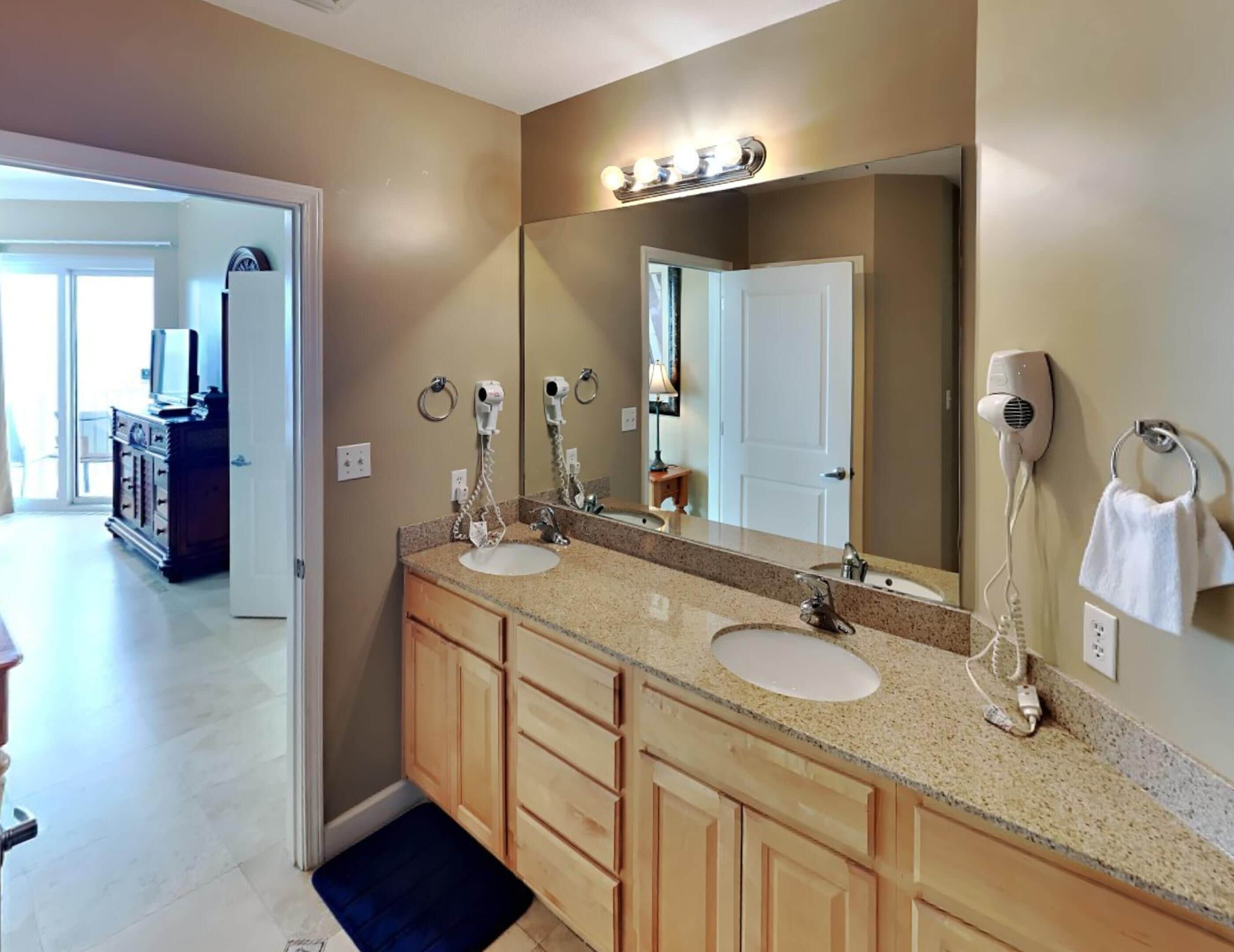 A bathroom with two sinks, a large mirror, and a hairdryer on the wall.