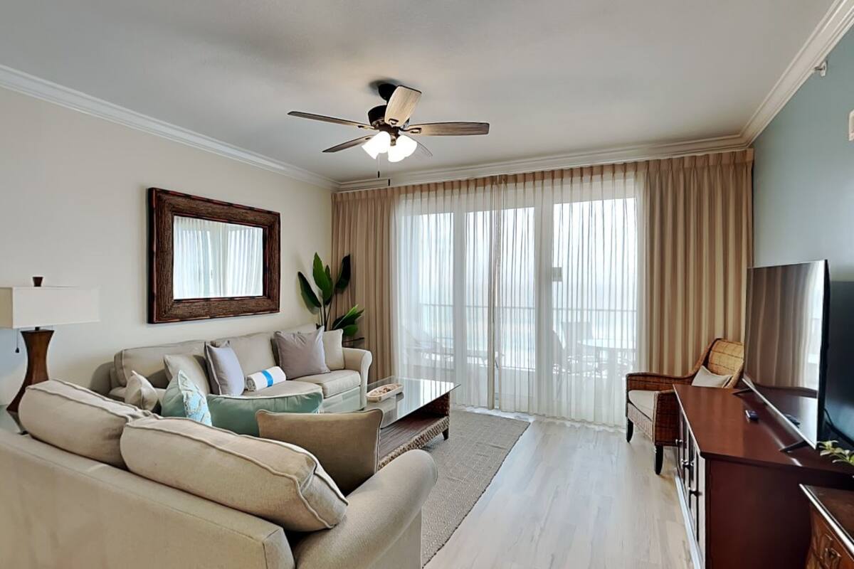 Sala de estar com sofá, mesa de centro, televisão e ventilador de teto.
