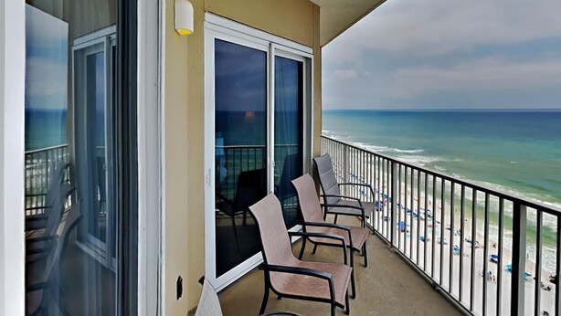 Ein Balkon mit Blick auf den Strand, ausgestattet mit einem Tisch und Stühlen.