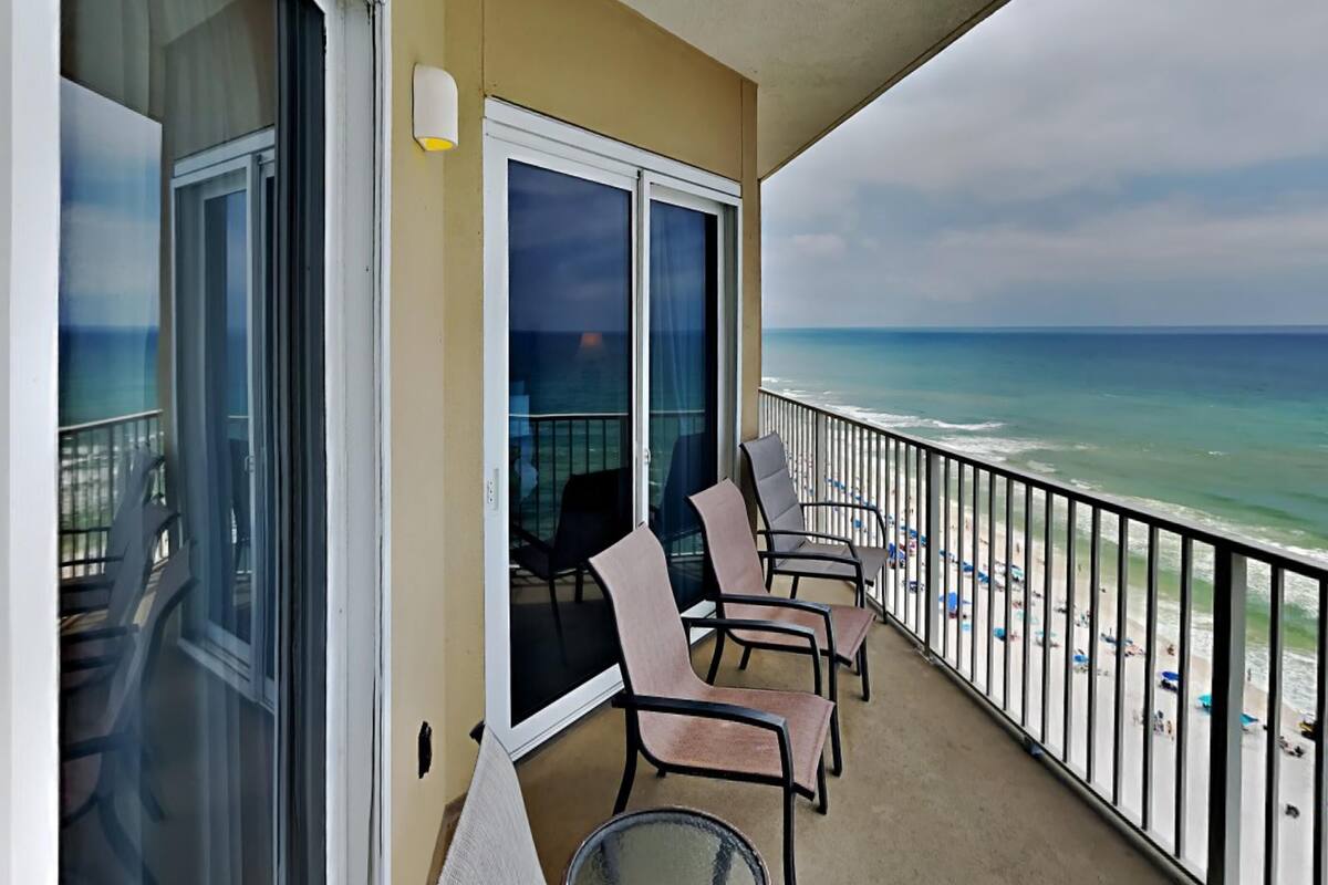 Varanda com vista para a praia, com mesa e cadeiras.