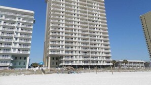 Ein hohes, mehrstöckiges Hotel mit Balkonen in Strandnähe.