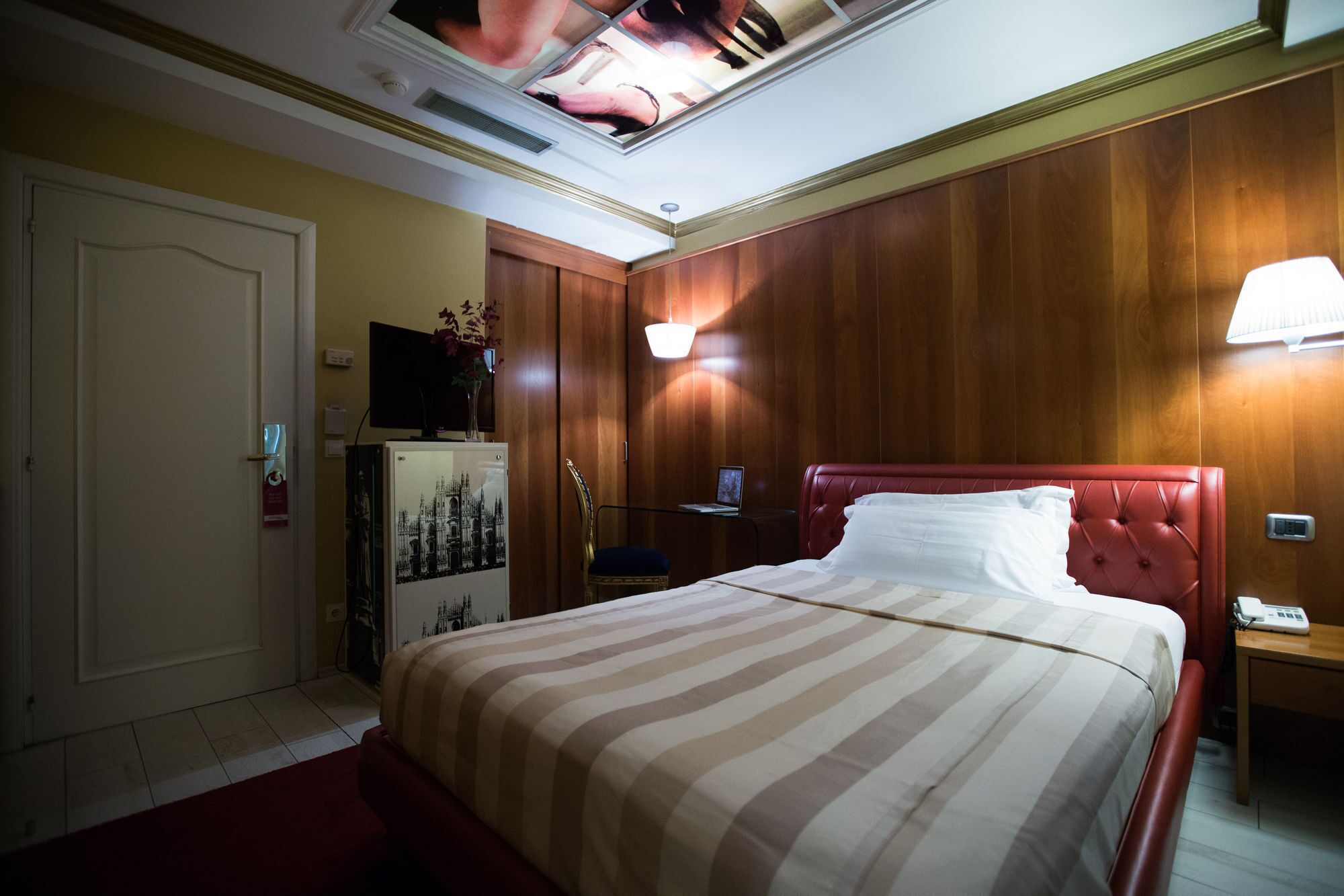 Et hotelværelse med seng, skrivebord, fjernsyn og minibar.