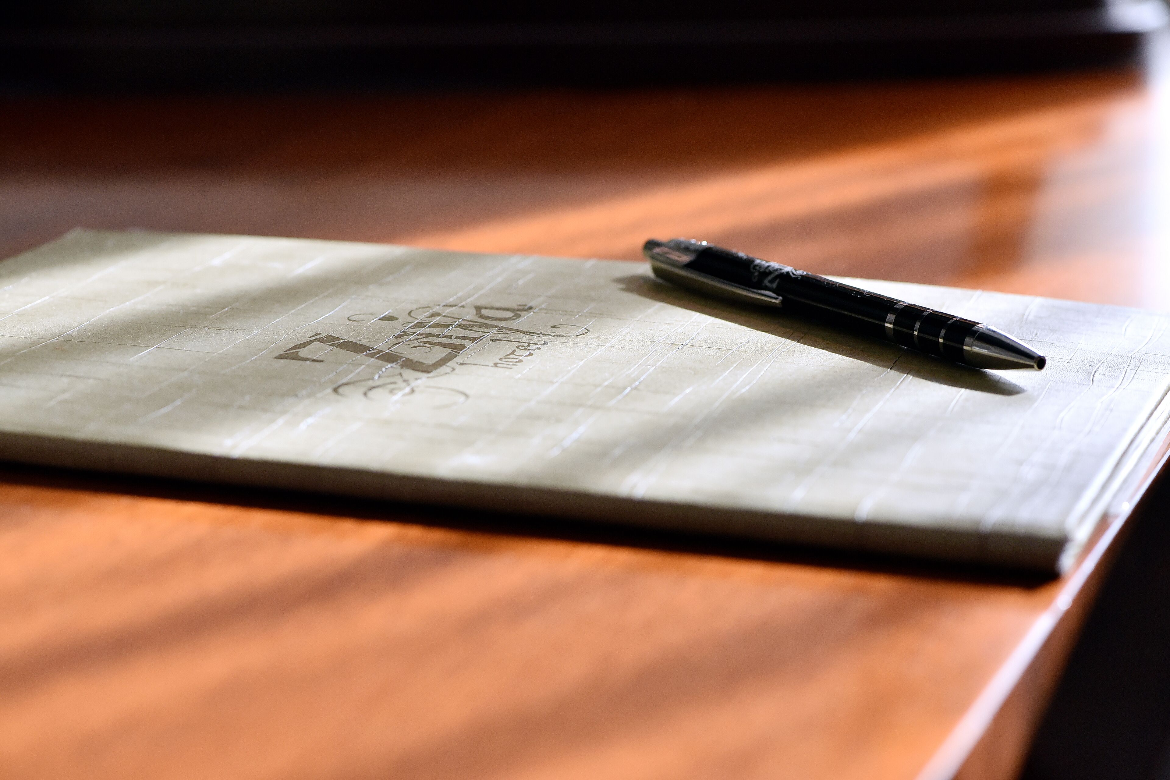A notebook with a pen on a wooden surface.