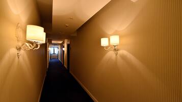 Un pasillo de hotel con dos apliques de pared y suelo alfombrado.