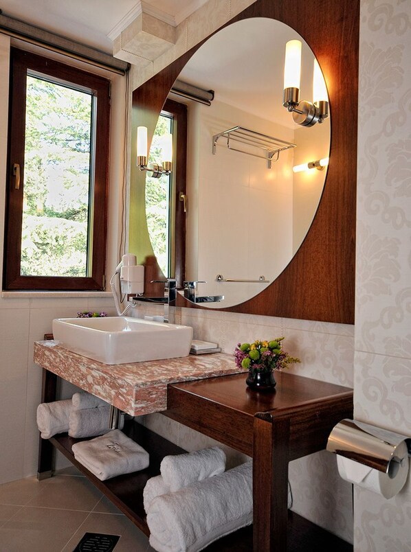 A bathroom with a large mirror, two sinks, a towel rack, and a window.