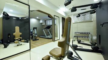 A gym with exercise equipment, a treadmill, and a mirrored wall.