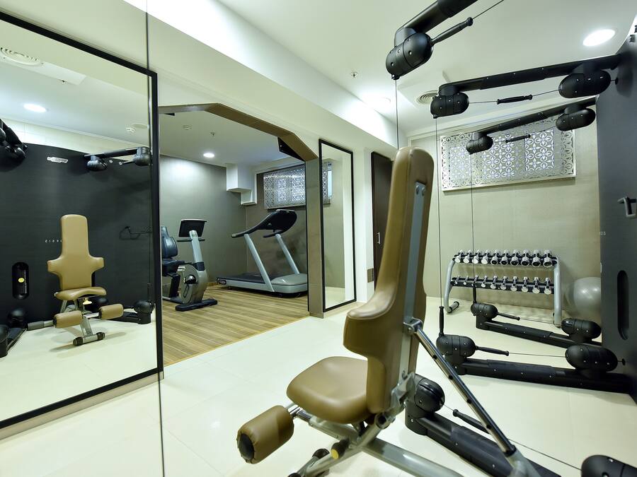 A gym with exercise equipment, a treadmill, and a mirrored wall.