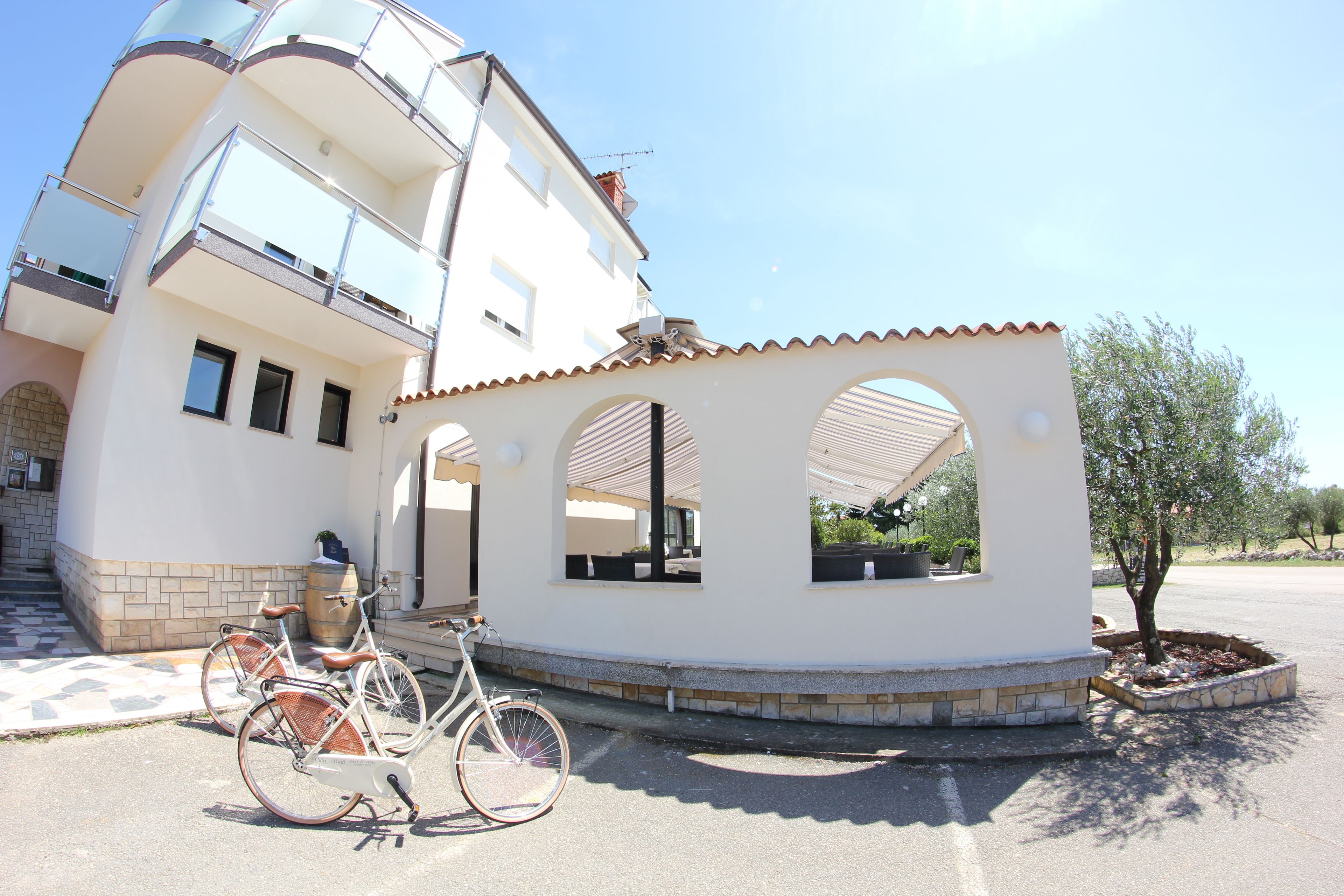 A multi-story building with a white facade, a balcony, and a small circular structure with windows.