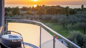 A balcony with wicker furniture, a stop sign, and a view of the sunset over the sea. - Villa Badi (Umag)