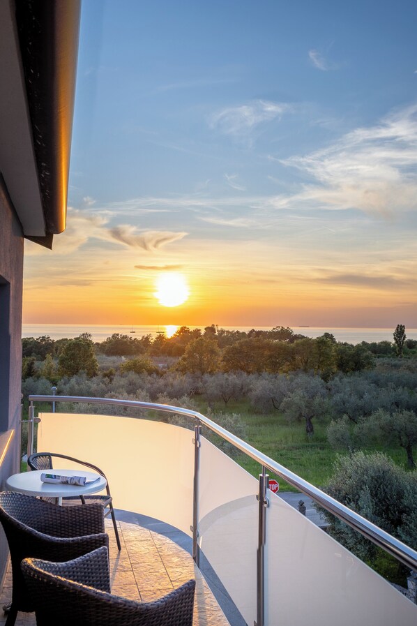 A balcony with wicker furniture, a stop sign, and a view of the sunset over the sea. - Villa Badi (Umag)