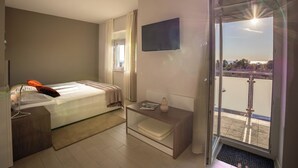 A hotel room with a bed, bedside table, TV, and a balcony with a view. - Villa Badi (Umag)