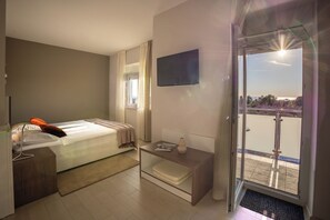 A hotel room with a bed, bedside table, TV, and a balcony with a view. - Villa Badi (Umag)