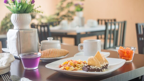 A dining table with plates of food, a vase with flowers, and a coffee cup.