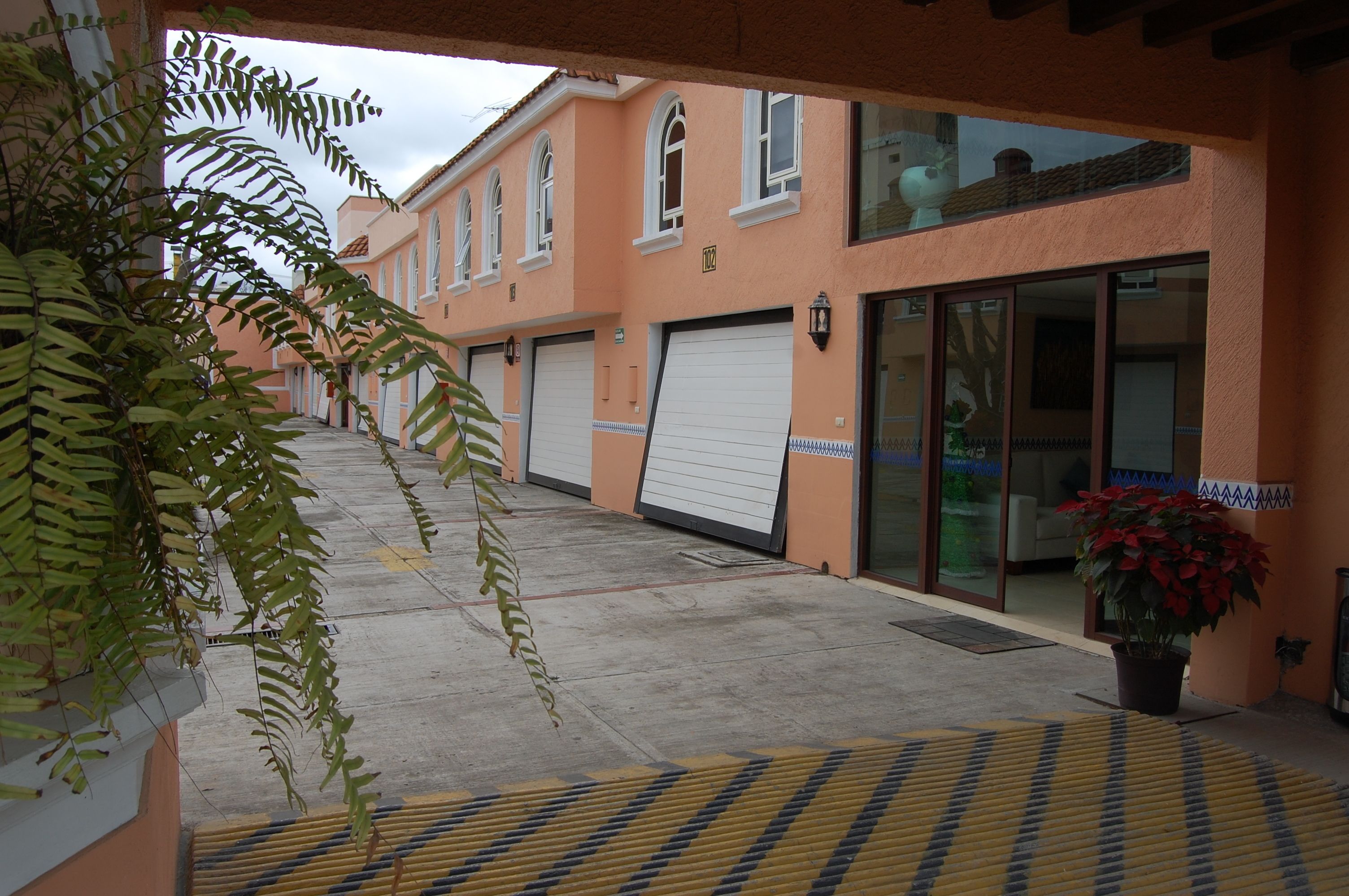 A building with a row of garage doors, a potted plant, and a clear sky.
