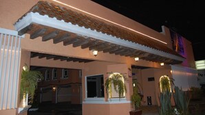 A building with a tiled roof, a white balcony, and a sign with a logo.