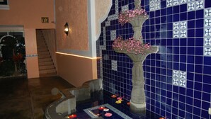 A blue-tiled wall with a decorative fountain and a staircase.