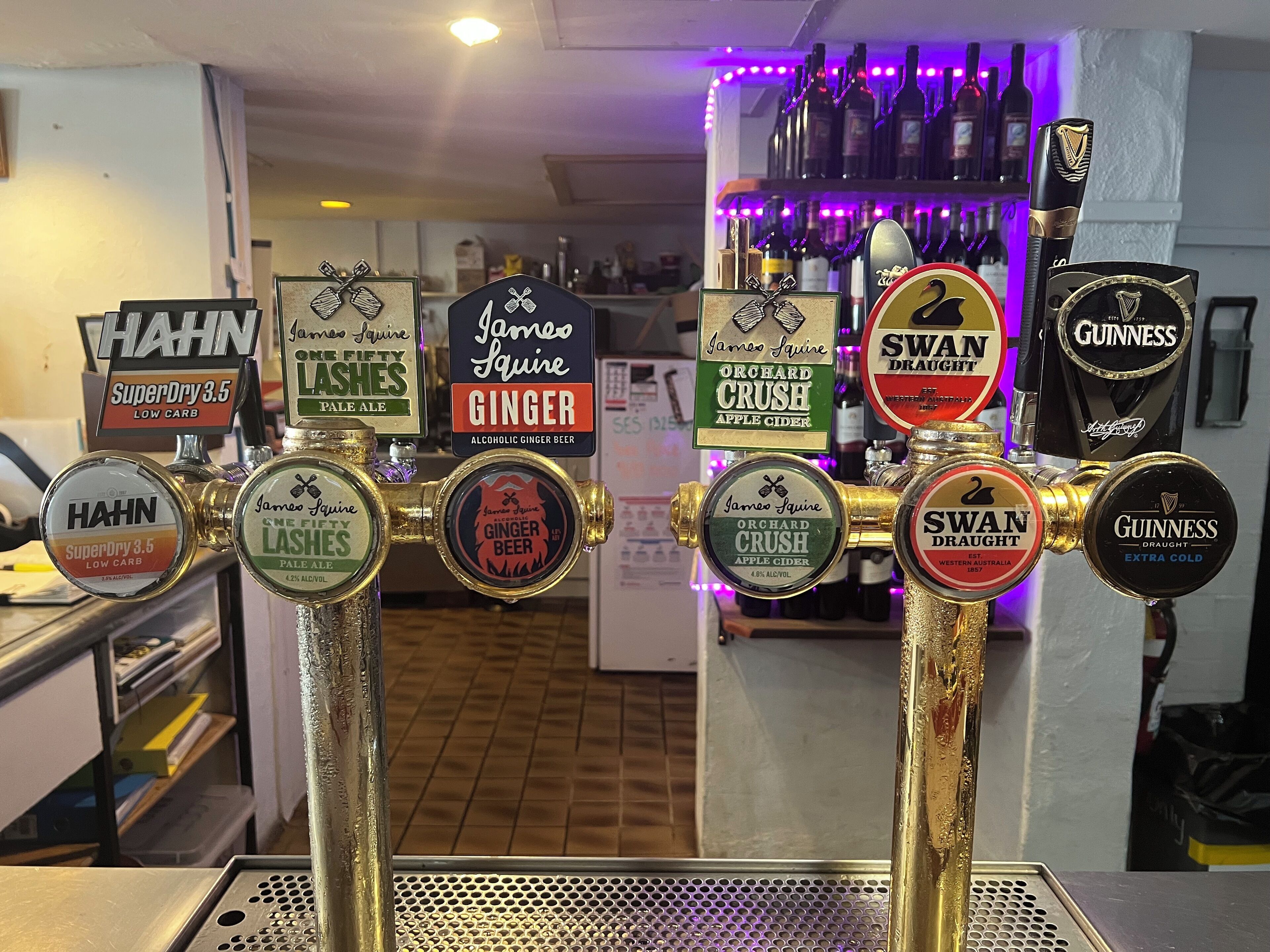 A bar area with multiple taps labeled with various beer and cider brands.