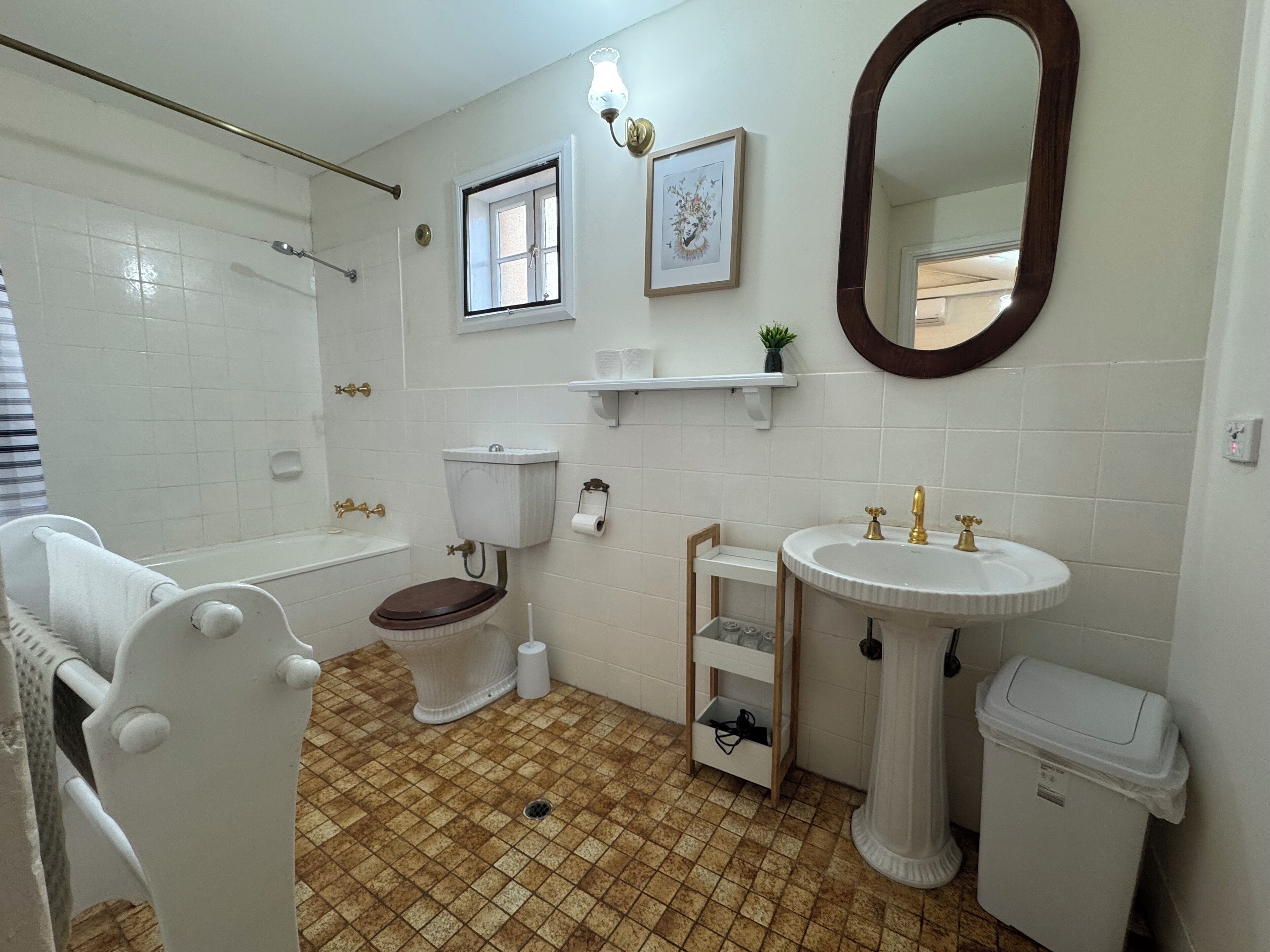 A bathroom with a toilet, sink, shower, and a mirror.