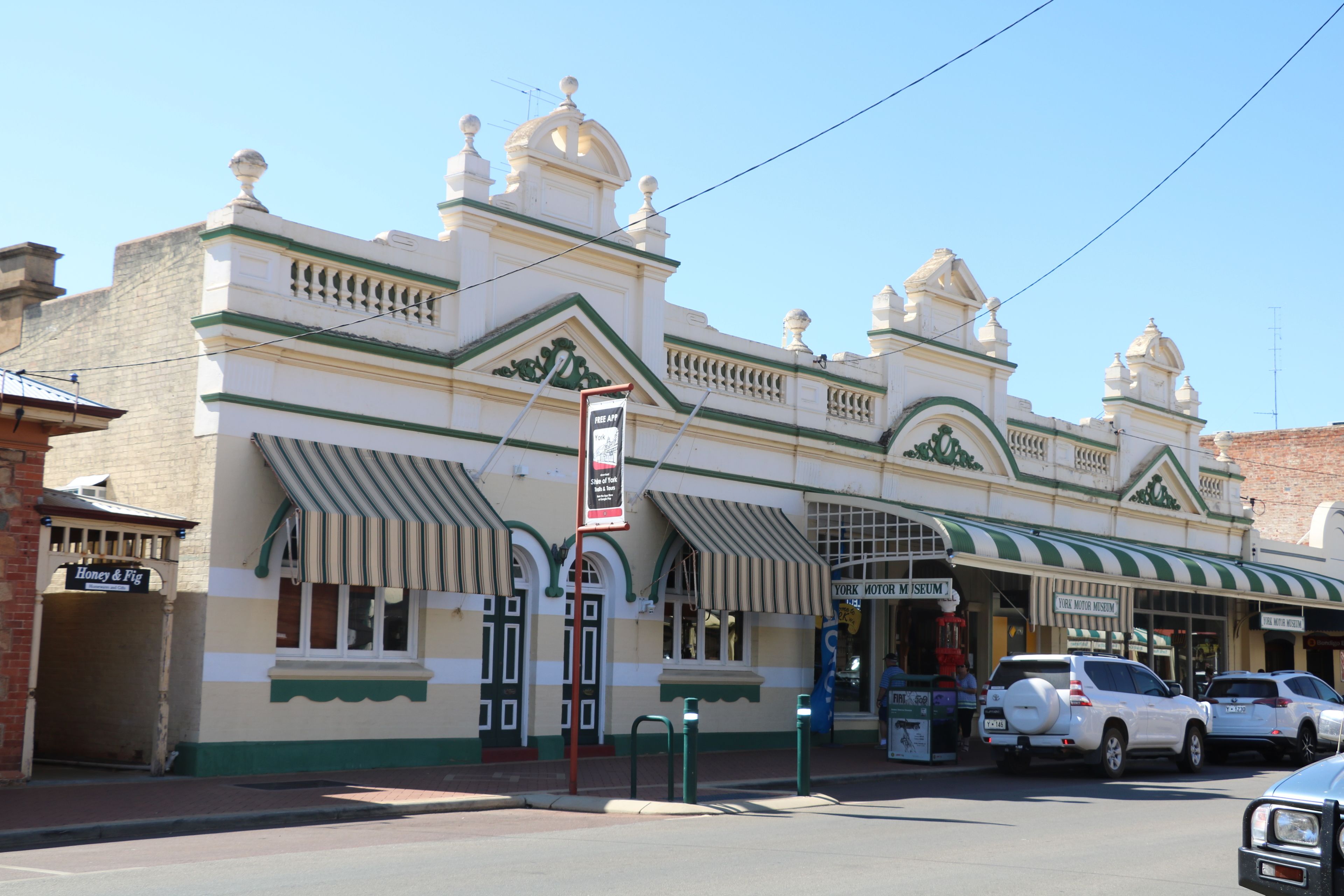 Ein Gebäude mit einer grün-weißen Fassade, einem Schild für das York Motor Museum und mehreren parkenden Autos.