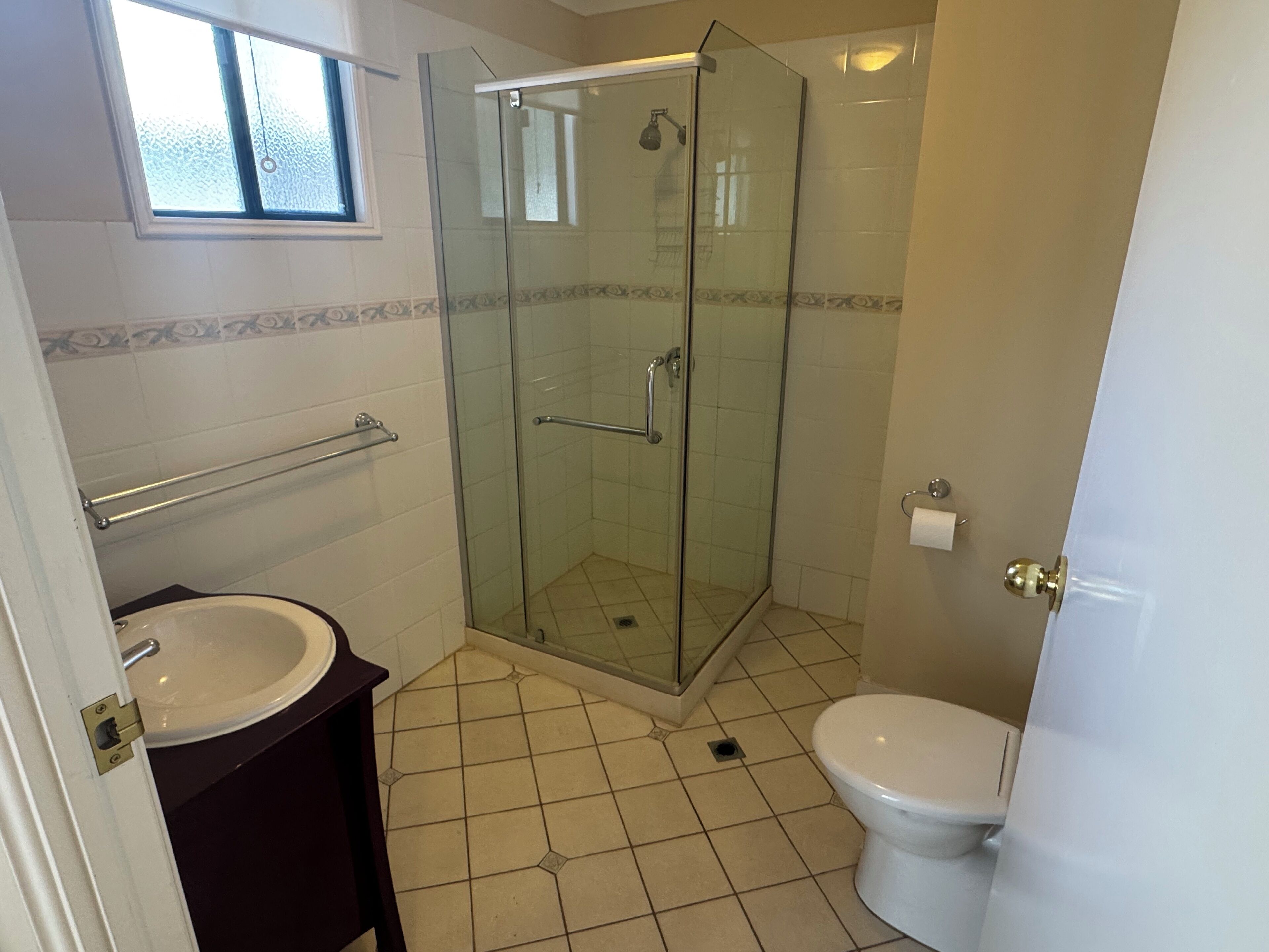 A bathroom with a glass-enclosed shower, a toilet, and a sink.