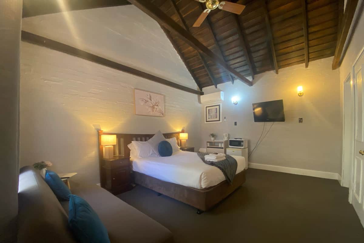 A bedroom with a bed, bedside tables, a TV, and a ceiling fan.