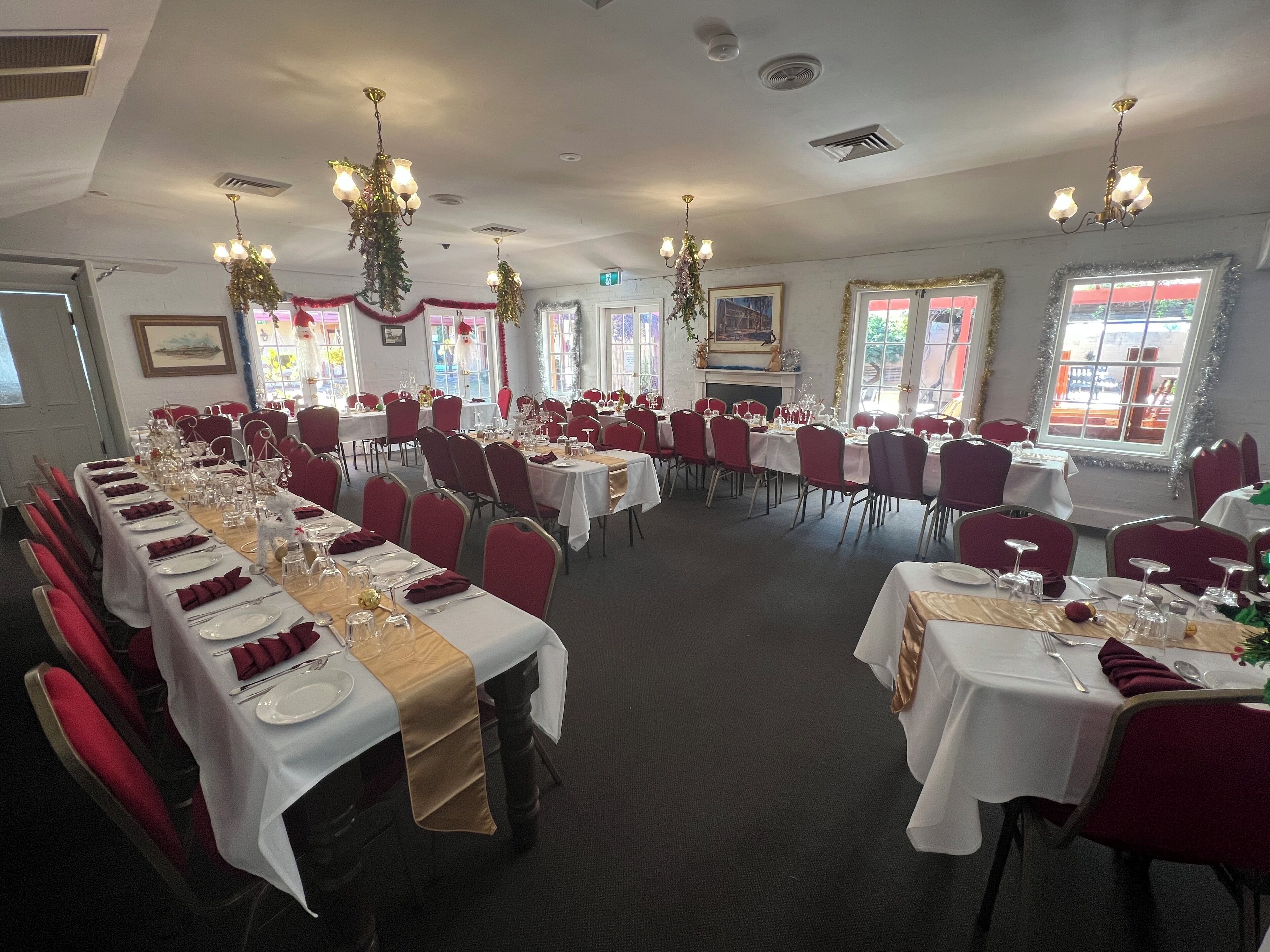 Un salón de banquetes con mesas largas dispuestas para un evento formal, con candelabros y sillas rojas.