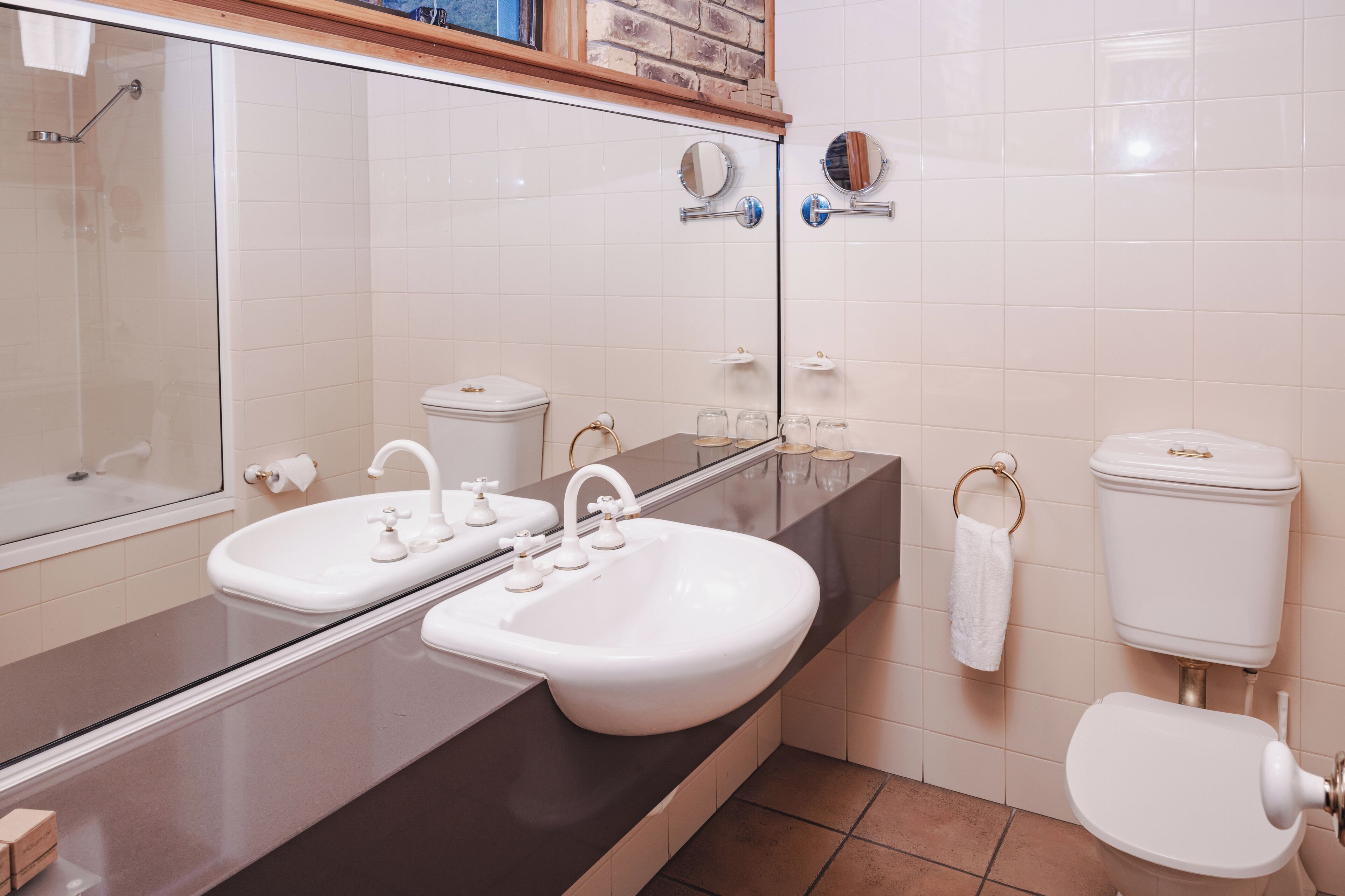 Un baño con lavamanos doble, inodoro, espejo y zona de ducha.