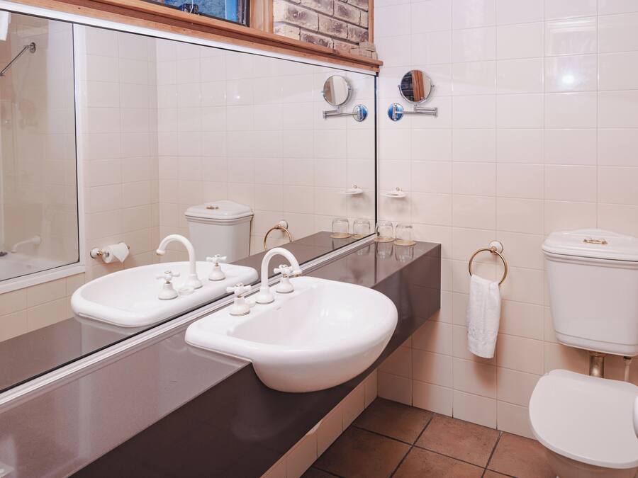 Un baño con lavamanos doble, inodoro, espejo y zona de ducha.