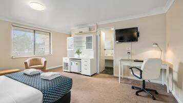 A hotel room with a bed, a desk, a chair, a television, and a bathroom.