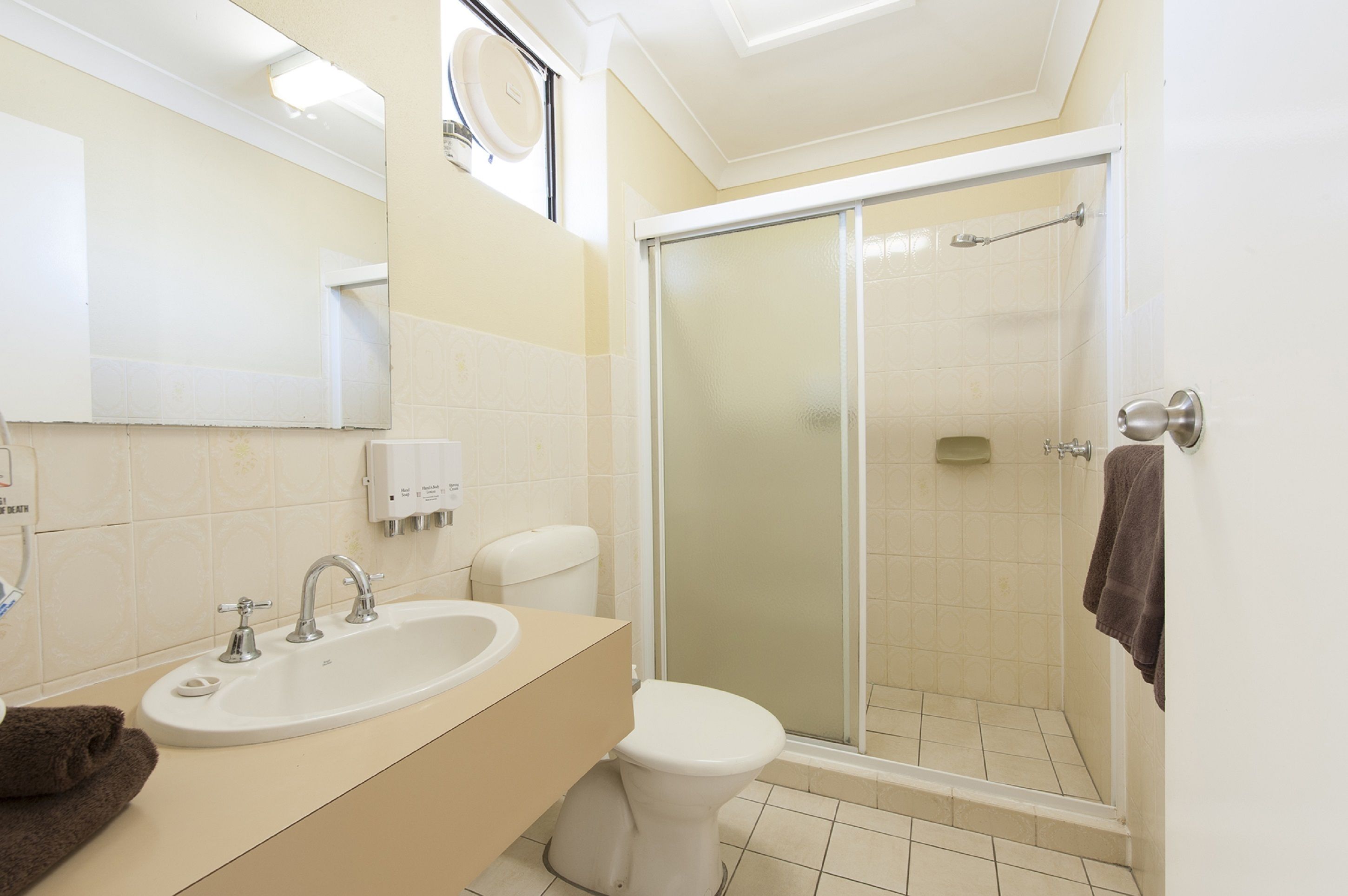 Un bagno con lavandino, water e box doccia in vetro.