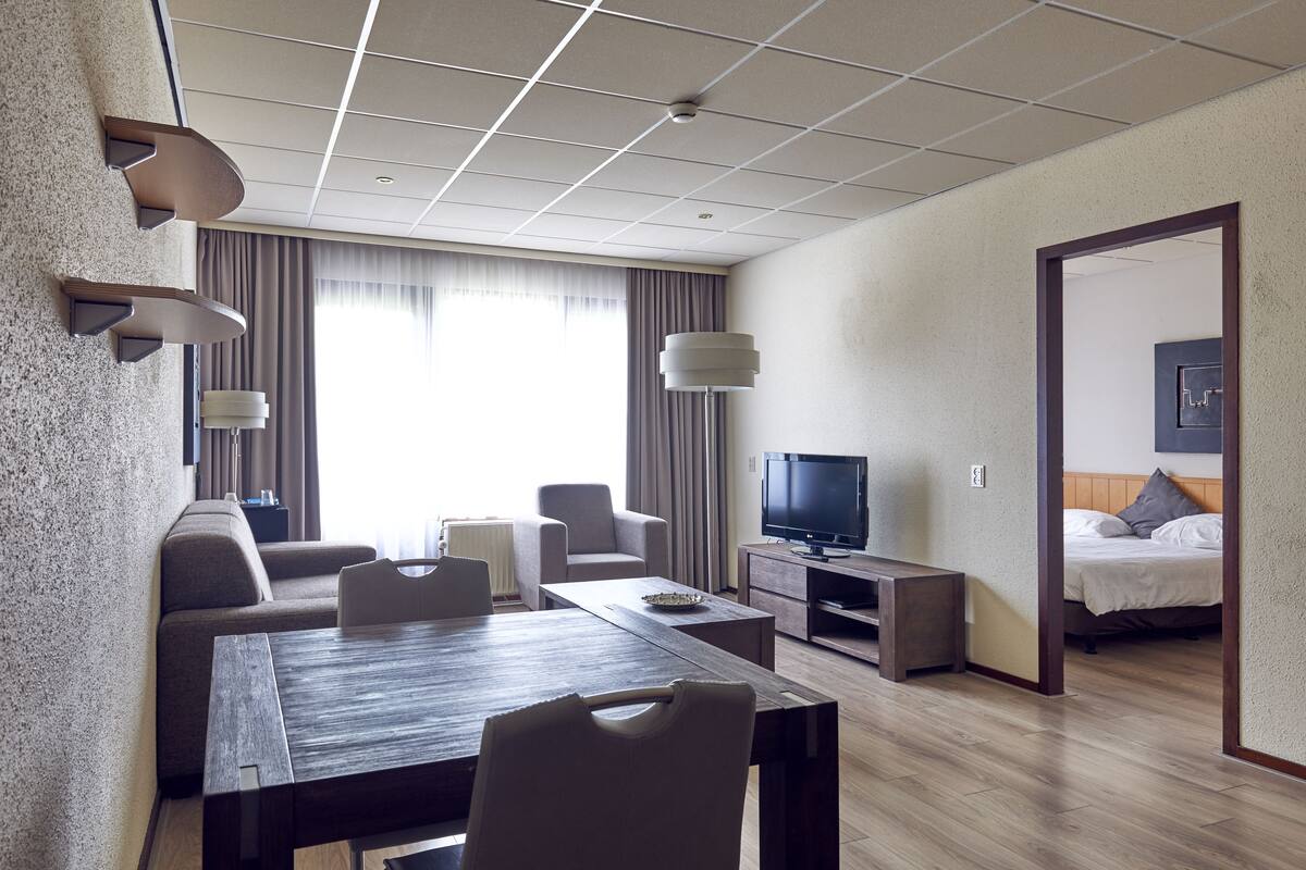 Ein modernes Hotelzimmer mit Essbereich, einer Couch, einem Fernseher und einem Bett.