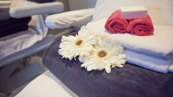 Een hotelkamer met een bed, een kussen, een opgerolde handdoek en een stuk zeep.