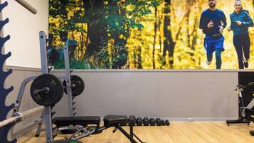 A gym with weightlifting equipment, a bench, and a wall with a nature-themed mural.