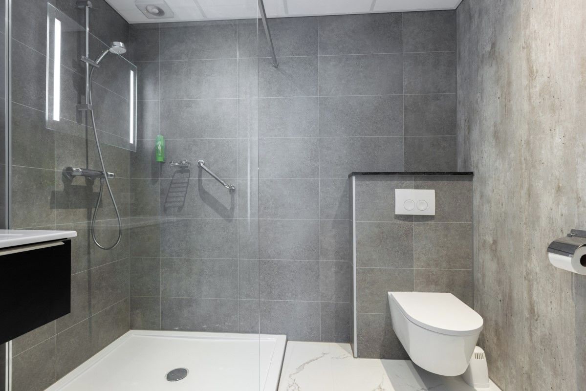 A modern bathroom with a shower, toilet, and a glass-enclosed walk-in shower.