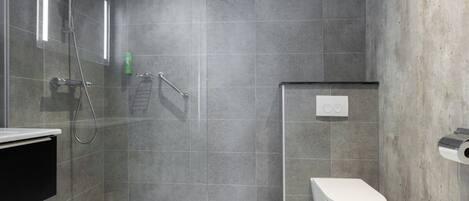 A modern bathroom with a shower, toilet, and a glass-enclosed walk-in shower.