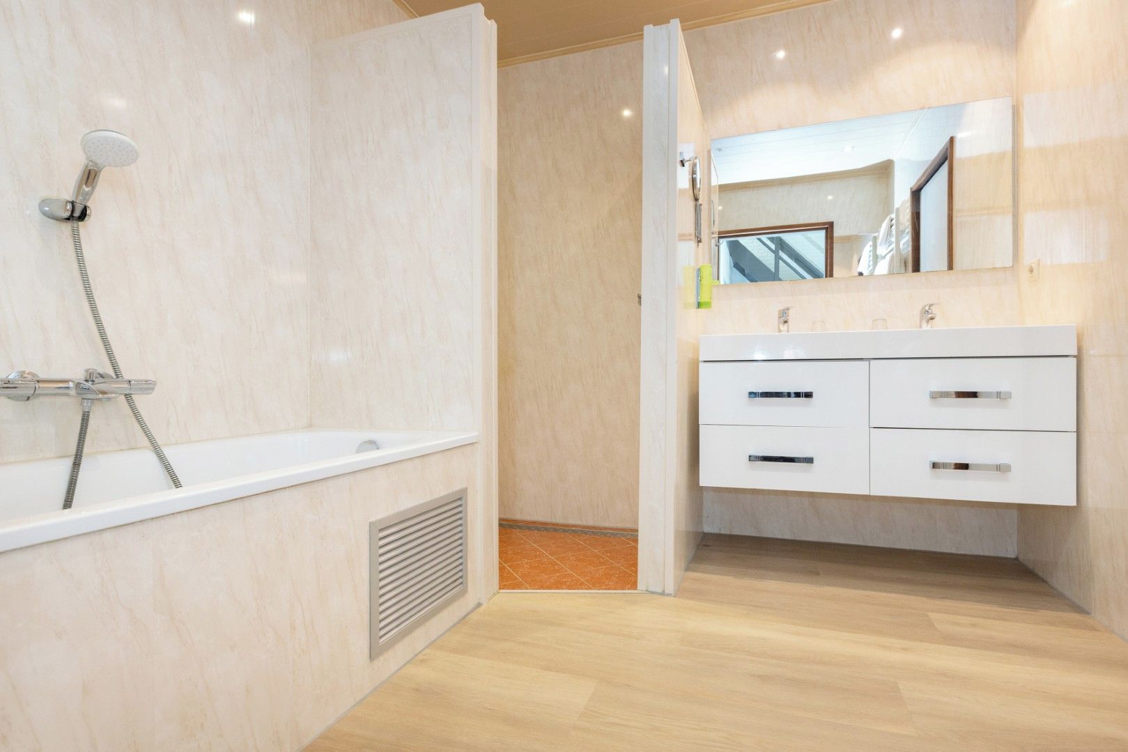 Ein modernes Badezimmer mit Badewanne, Dusche und Waschtisch mit Schubladen.