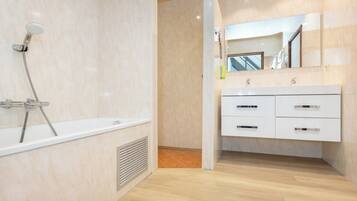 Ein modernes Badezimmer mit Badewanne, Dusche und Waschtisch mit Schubladen.