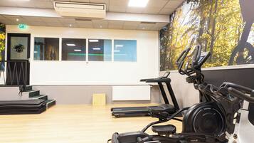 Un gimnasio con equipo de ejercicio, una pared con cuadros enmarcados y una escalera.